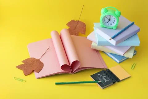 Back to school, alarm clock, open blank notebook, stack of books and pencils Stock Photos