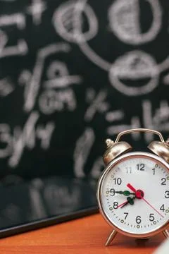 Back to school concept, alarm clock on school board background, university Stock Photos