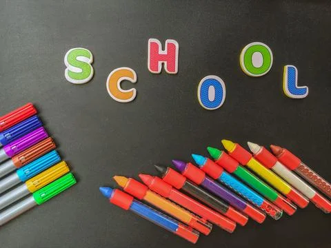 Back to school concept. Colored pencils on black background with the word sch Stock Photos