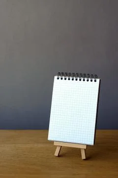 Back to school concept, open notebook on miniature easel on wooden surface on Stock Photos