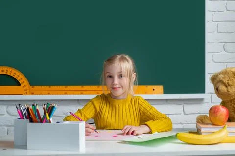 Back to school. Cute pupil girl drawing at the desk. Child in the class room Stock Photos
