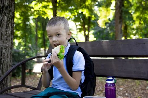 Back to school. An elementary school student has a sandwich after class.   Stock Photos
