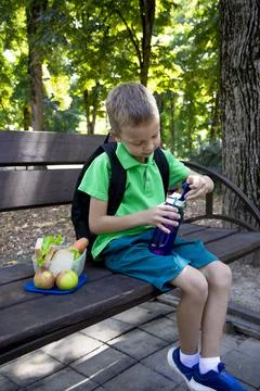 Back to school. An elementary school student drinks water from a bottle Stock Photos
