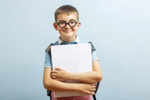 Back to school. Happy elementary school student in eyeglasses hugging a book  Stock Photos