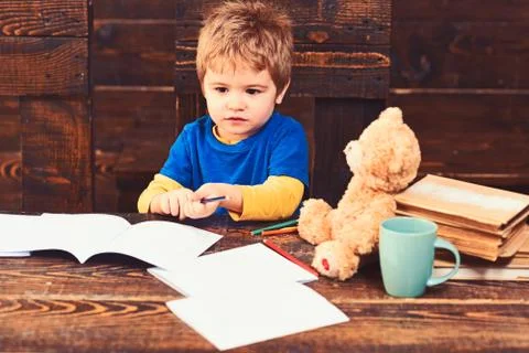 Back to school. Kid looking at copybooks on wooden table. Small concentrated boy Stock Photos