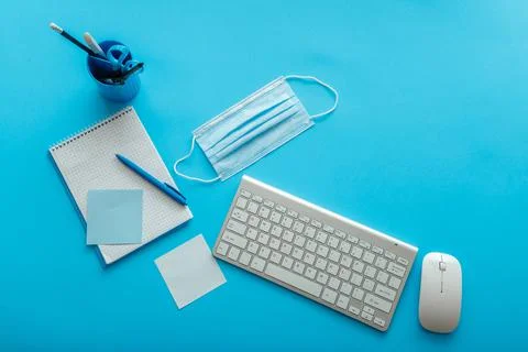 Back to school layout concept. Blue work desk with covid medical face mask Stock Photos