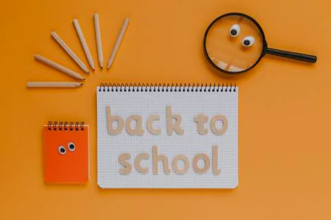 Back to school lettering on a notebook, with animated objects. Orange background Stock Photos