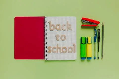 Back to school letters on a notebook with other stuff and green background. Stock Photos