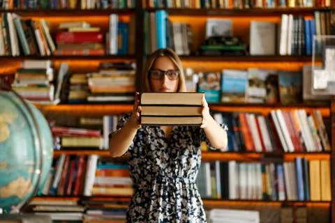 Back to school library concept. Student girl holding book on her hands on Stock Photos