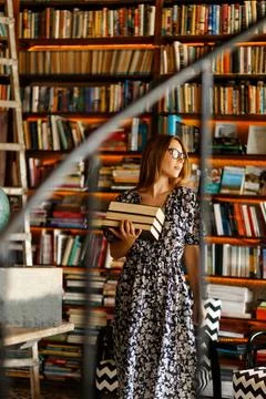 Back to school library concept. Student girl holding book on her hands on Stock Photos
