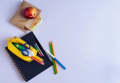 Back to School Material. Pencils, notebook and sandwich on purple background. Stock Photos