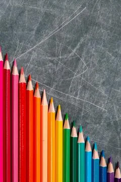 Back to school: multicolored pencils lay on black chalkboard, short focus, pa Stock Photos