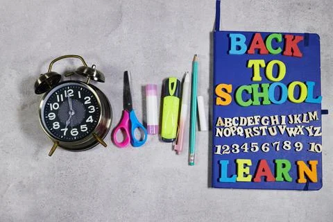 Back to School Notebook With Alarm Clock and Colorful Supplies on Gray Backgroun Stock Photos