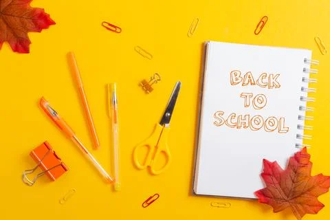 Back to school. Notepad, scissors, clips and pencils on yellow desktop backgr Stock Photos