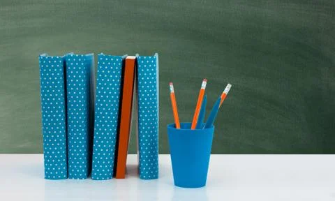 Back to school, pile of books with empty green school board background. Dista Stock Photos