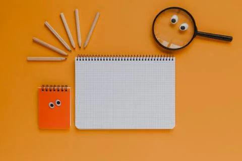 Back to school stuff, notebook with copyspace in the middle. Orange background. Stock Photos