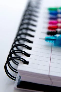 Back to school supplies, multi colored pens and a spiral notebook Stock Photos
