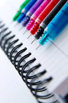 Back to school supplies, multi colored pens and a spiral notebook Stock Photos