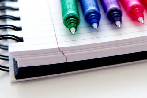 Back to school supplies, multi colored pens and a spiral notebook Stock Photos