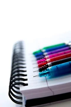 Back to school supplies, multi colored pens and a spiral notebook Stock Photos