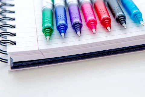Back to school supplies, multi colored pens and a spiral notebook Stock Photos