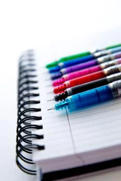 Back to school supplies, multi colored pens and a spiral notebook Stock Photos