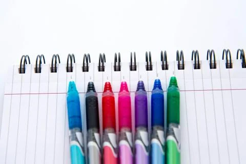 Back to school supplies, multi colored pens and a spiral notebook Stock Photos