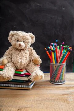 Back to school. Teddy bear and colorful pencils and notebooks on blackboard b Stock Photos