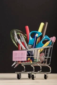 Back to school template with multiple stationery in trolley against black Stock Photos