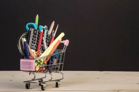 Back to school template with multiple stationery in trolley against black Stock Photos
