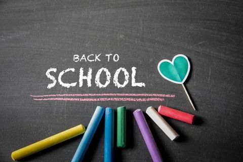 Back to school. Text and colored pieces of chalk on a dark blackboard Stock Photos