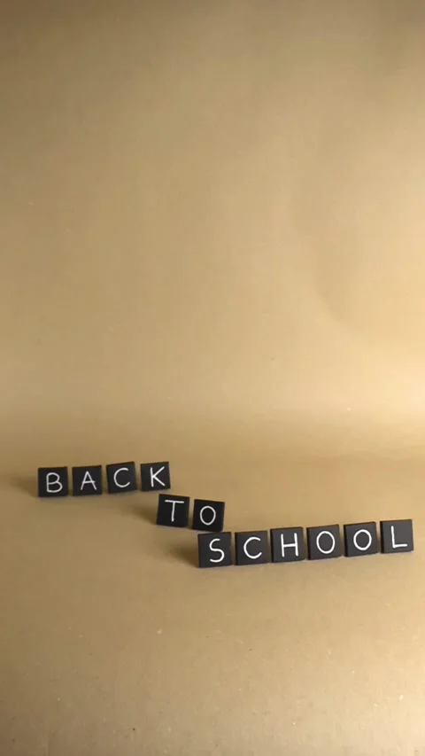 Back to school text on black tiles on brown paper background Stock Footage 343932156