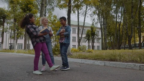 Back to school. Three Friends With Backpacks huging and laughing in front of Stock Footage 112831664