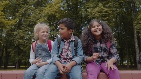 Back to school. Three Friends With Backpacks huging and laughing near school Stock Footage 113481640