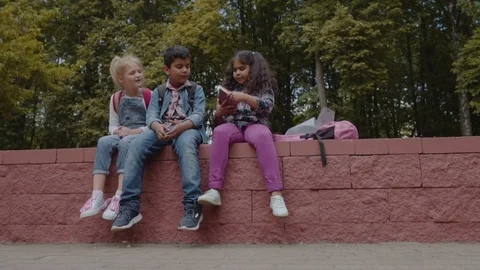 Back to school. Three Friends With Backpacks huging and laughing near school Stock Footage 113481702