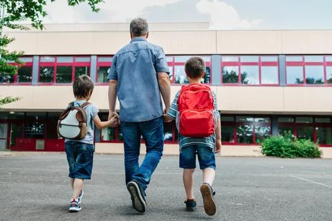 Back to school. View from the back of a happy dad escorts his sons Stock Photos