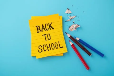 Back to school word on yellow note with color pencils on blue background Stock Photos