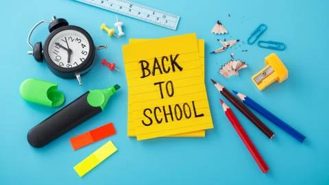 Back to school word on yellow note with clock and school supplies Stock Photos