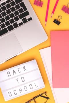 Back to school. Workspace with lightbox, laptop and stationery on a yellow ba Stock Photos