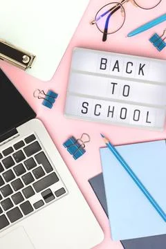 Back to school. Workspace with lightbox, laptop and office supplies on a pink Stock Photos