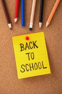 Back to school on yellow note with color pencils on cork board background, to Stock Photos