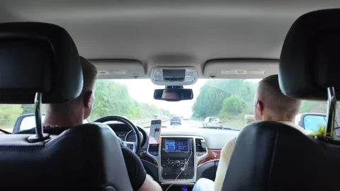Back-seat Car View with Driver, Passenger, and Hand Reaching Toward Dashboard Vídeos de archivo 347683158