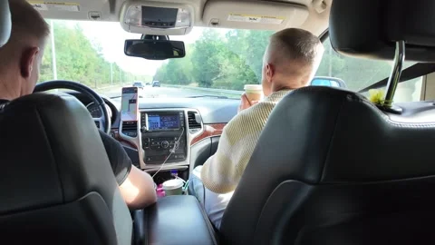 Back-seat Car View with Driver, Passenger, Forest Road, and Cup 库存影片 347683264