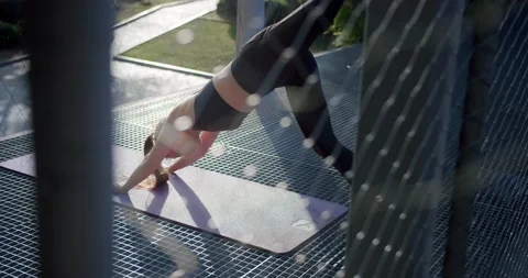 Back shoot through net fence of powerful woman doing workout pushing strong leg Stock Footage 117543140