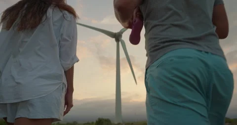 Back Shot of a Man Carrying his Child and Walkingin a Wind farm with his family Stock Footage 250970337