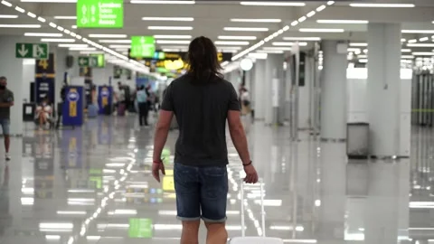 Back shot of a middle aged man walking through the airport terminal carrying  Video stock 136393614