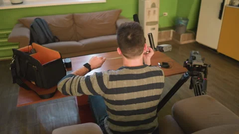 Back shot of Studio guy adjusting camera lens on tripod preparing for video Vídeo Stock 317591742