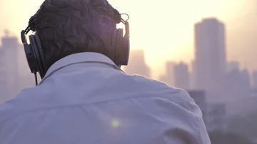 Back shot of a young Indian man wearing headphones and listening to music Stock-Footage 85876987