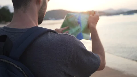 Back Shot of Young Man 4K Searching iOn Map Paper Guide on Beach. Stock Footage 109088799