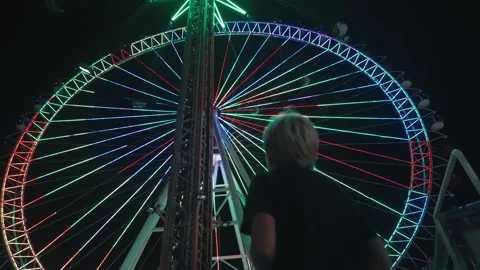 Back side of a boy standing at the amusement park at night Stock Footage 253849105